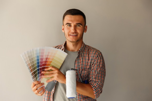 Seorang pria sedang memegang color palette dan kuas cat